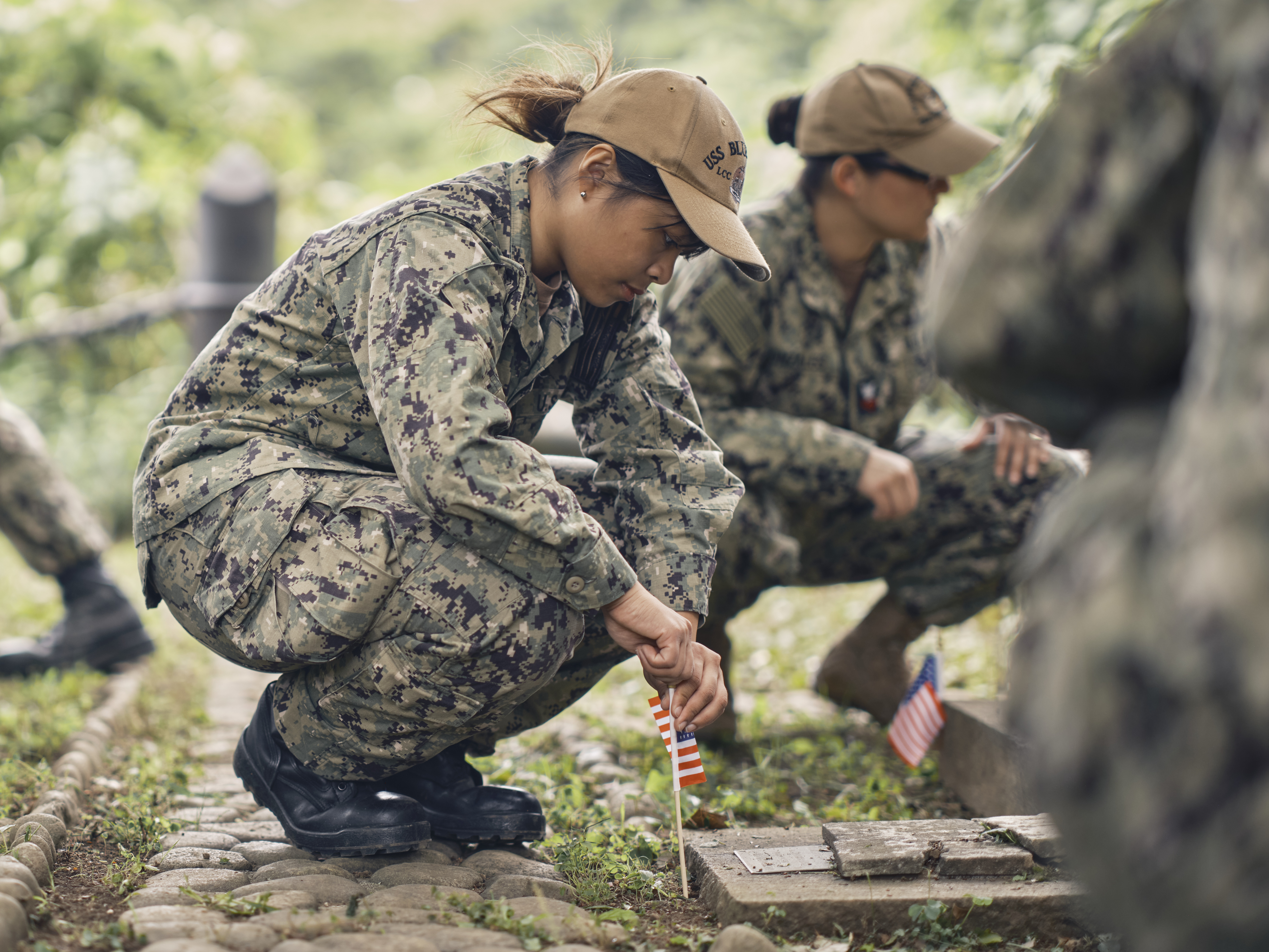 Sailors from USS Blue Ridge (LCC 19) places an American flag at a memorial to U.S. service members at the Yokohama General Foreign Cemetery.