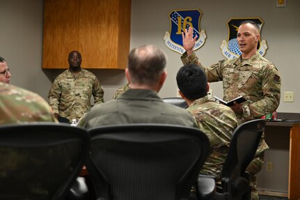 The command chief speaks to a group at a table.