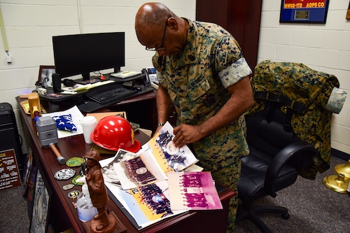 U.S. Marine Corps Master Gunnery Sgt. Terrail Dickerson, Marine Corps Detachment Goodfellow Air Force Base Fire Company senior enlisted advisor, looks through old photos of his time aboard Naval Air Station Millington in his office at the Louis F. Garland Department of Defense Fire Academy on Goodfellow AFB, Texas, May 8, 2024. Dickerson is the last individual in the Department of the Navy who attended training at NAS Millington, and as he leaves the Marine Corps, an important chapter of history for firefighting in the Department of the Navy is closing. (U.S. Marine Corps photo by Cpl. Jessica Roeder)