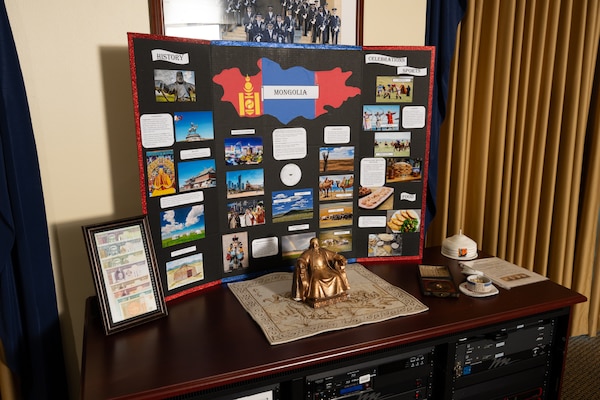 A trifold posterboard shows facts about Mongolia with a small statue of a seated figure and other items on a tabletop