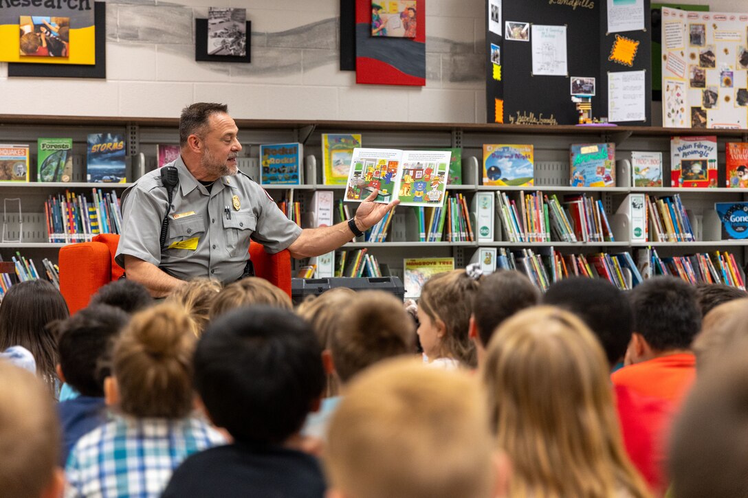 Man reading water safety book to children.