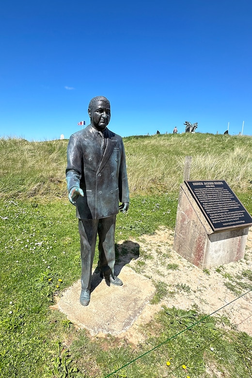 A statue of a person in position on a beach.