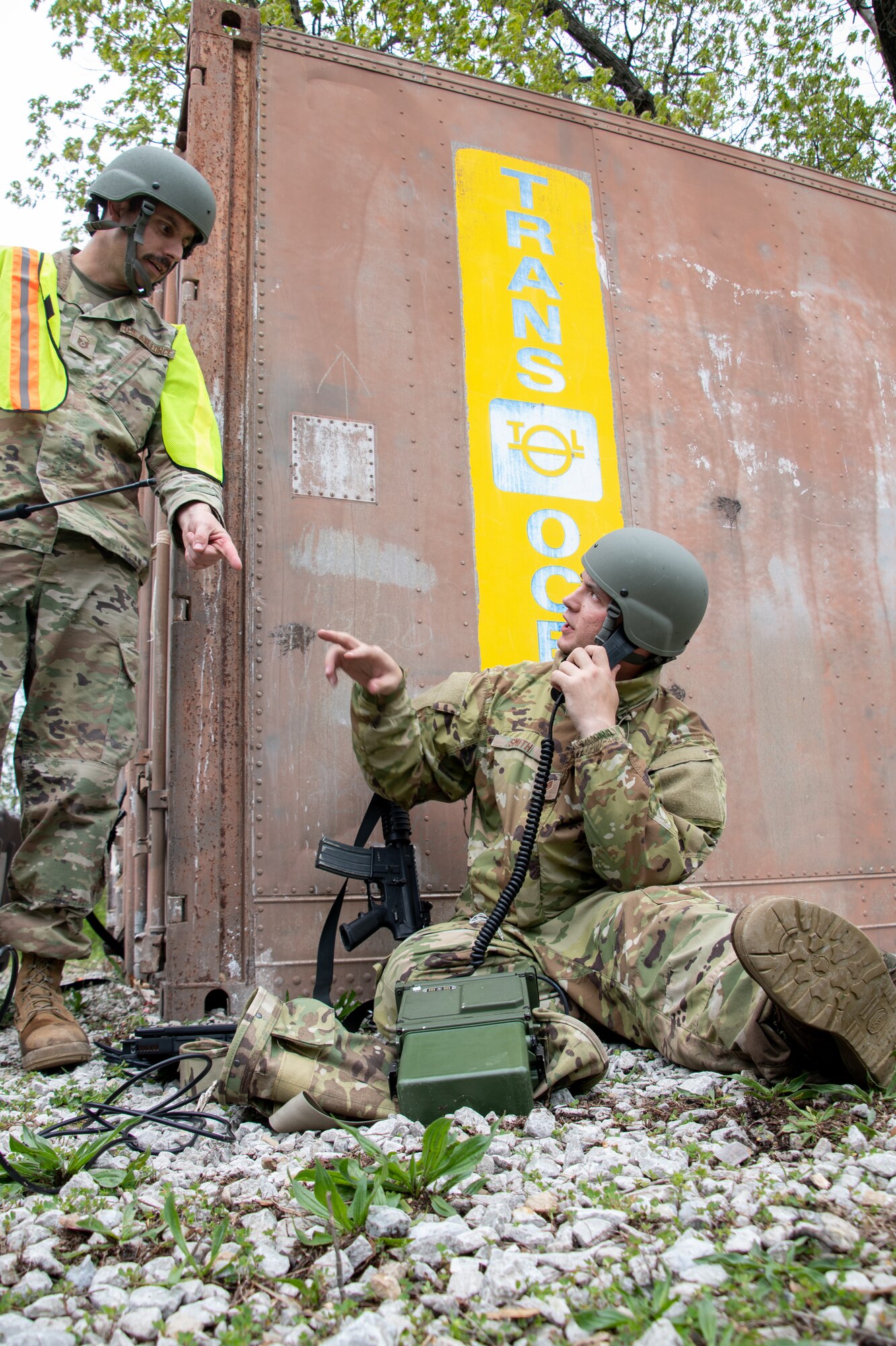 U.S. Air National Guard Airmen use a portable field radio next to a metal building.