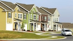 Four multicolor, two-story houses with a white car driving in front of them.