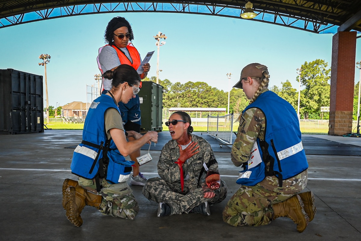 Two medical member provides care to a casualty role player to simulate a medical exercise.