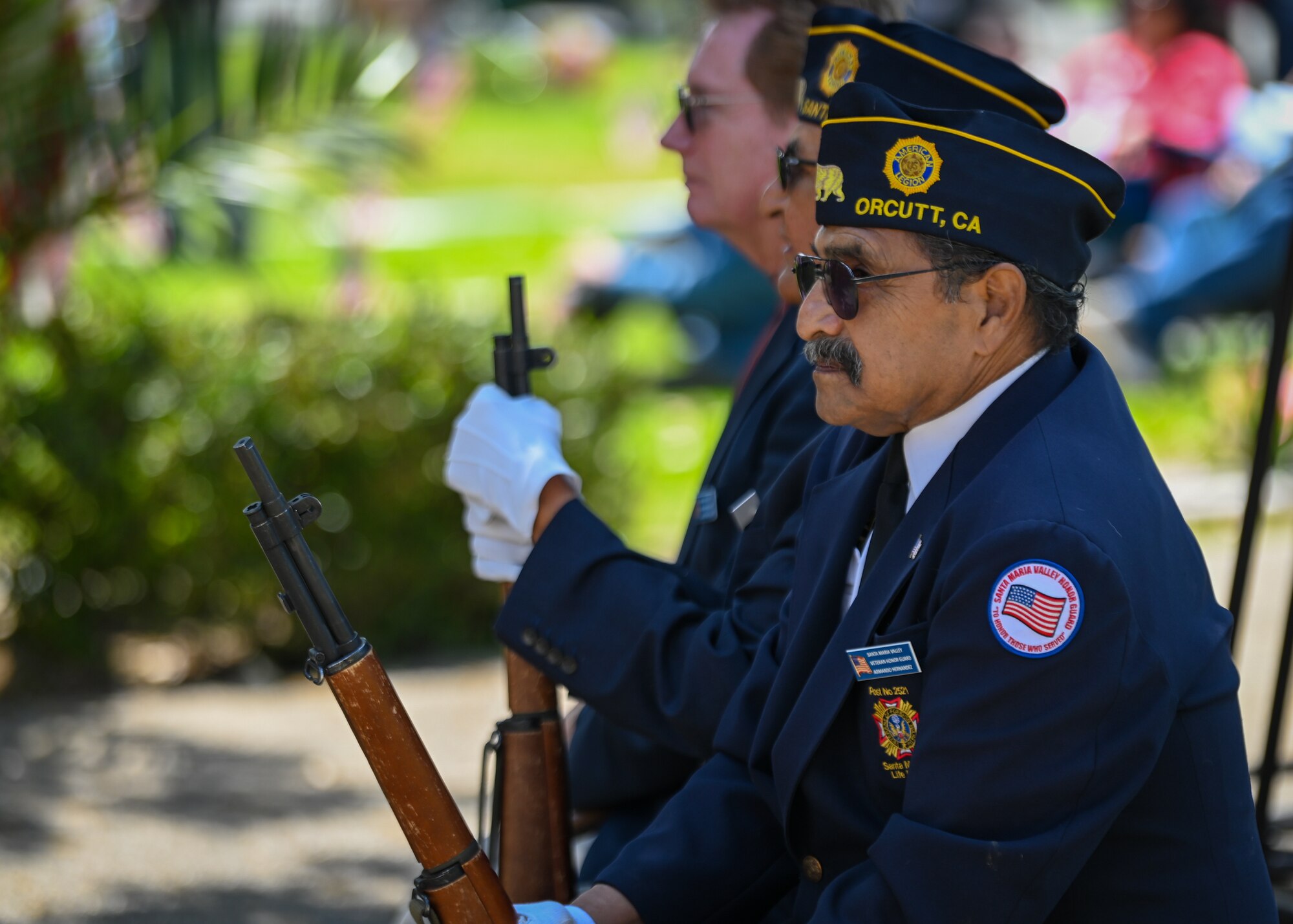 A man sits with a rifle.