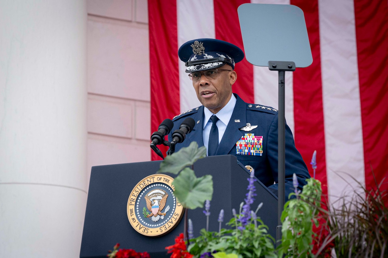 A military officer speaks from behind a podium.