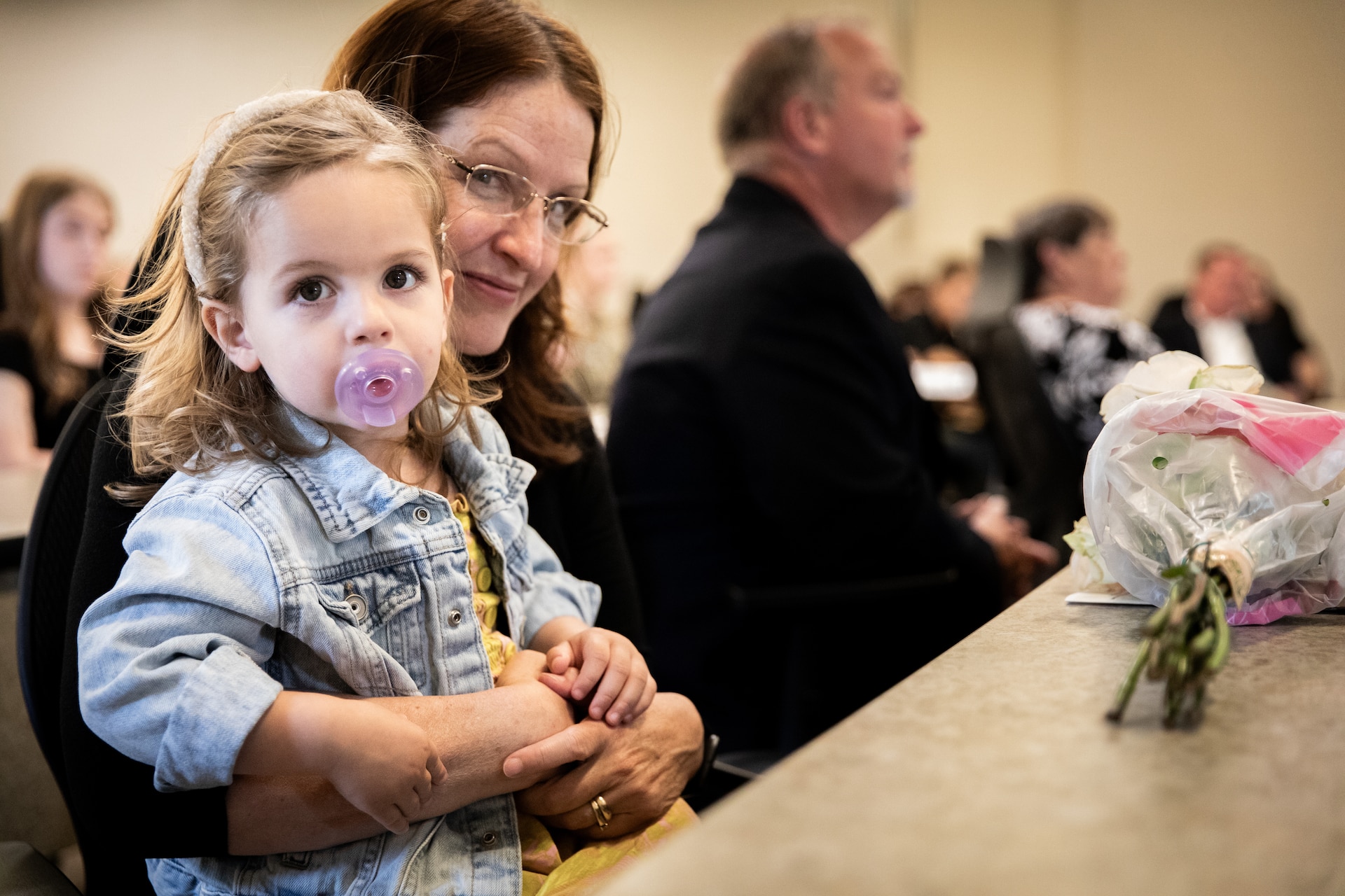Retired 1st Sgt. Angela Wilkins, daughter-in-law to Chief Warrant Officer 5 Joe Wilkins, holds her grand-daughter, Ava Wilkins, at the building renaming ceremony in remembrance of Joe Wilkins at the Wendell H. Ford Regional Training Center (WHFRTC) in Greenville, Kentucky on May 24, 2024. Joe Wilkins was one of three full-time employees at WHFRTC and helped form it in to a major state training site. (U.S. Army National Guard photo by Andy Dickson)