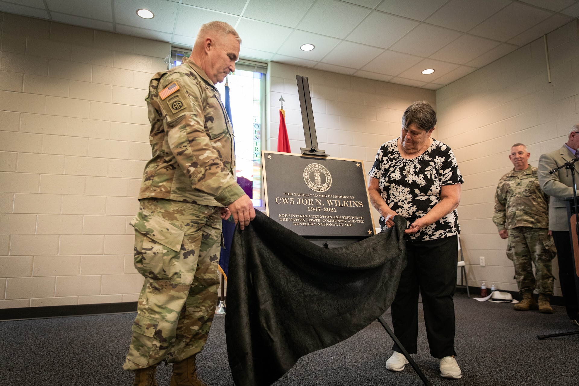 U.S. Army Maj. Gen. Haldane Lamberton, the adjutant general of the Kentucky National Guard, and Frances Wilkins, widow of Chief Warrant Officer 5 Joe Wilkins, unveils the plaque for the building renaming in remembrance of Joe Wilkins at Wendell H. Ford Regional Training Center (WHFRTC) in Greenville, Kentucky on May 24, 2024. Joe Wilkins was one of the three full-time employees who made WHFRTC a major state training site. (U.S. Army National Guard photo by Andy Dickson)