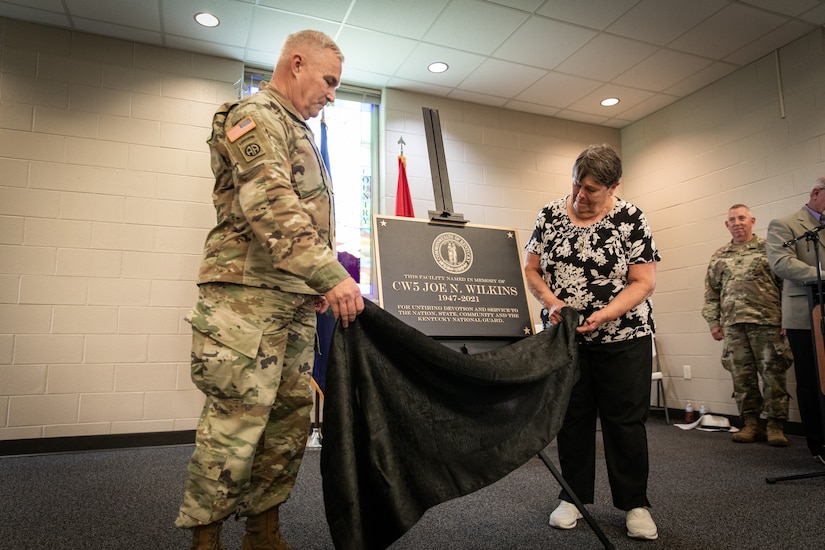 U.S. Army Maj. Gen. Haldane Lamberton, the adjutant general of the Kentucky National Guard, and Frances Wilkins, widow of Chief Warrant Officer 5 Joe Wilkins, unveils the plaque for the building renaming in remembrance of Joe Wilkins at Wendell H. Ford Regional Training Center (WHFRTC) in Greenville, Kentucky on May 24, 2024. Joe Wilkins was one of the three full-time employees who made WHFRTC a major state training site. (U.S. Army National Guard photo by Andy Dickson)