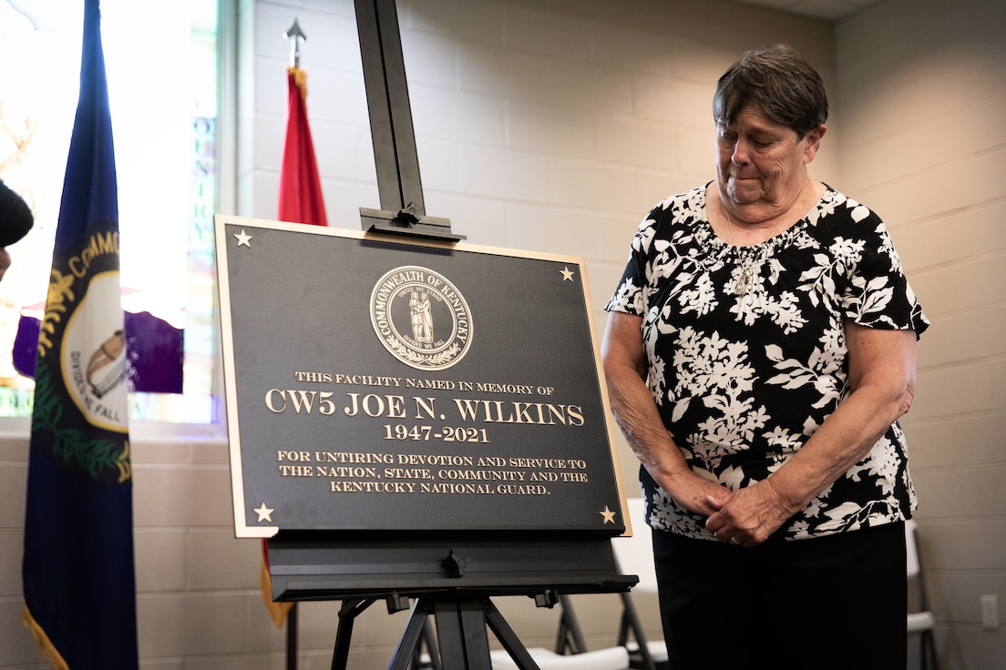 Frances Wilkins, widow of Chief Warrant Officer 5 Joe Wilkins, unveils the plaque for the building renaming in remembrance of Joe Wilkins at Wendell H. Ford Regional Training Center (WHFRTC) in Greenville, Kentucky on May 24, 2024. Joe Wilkins was one of the three full-time employees who made WHFRTC a major state training site. (U.S. Army National Guard photo by Andy Dickson)