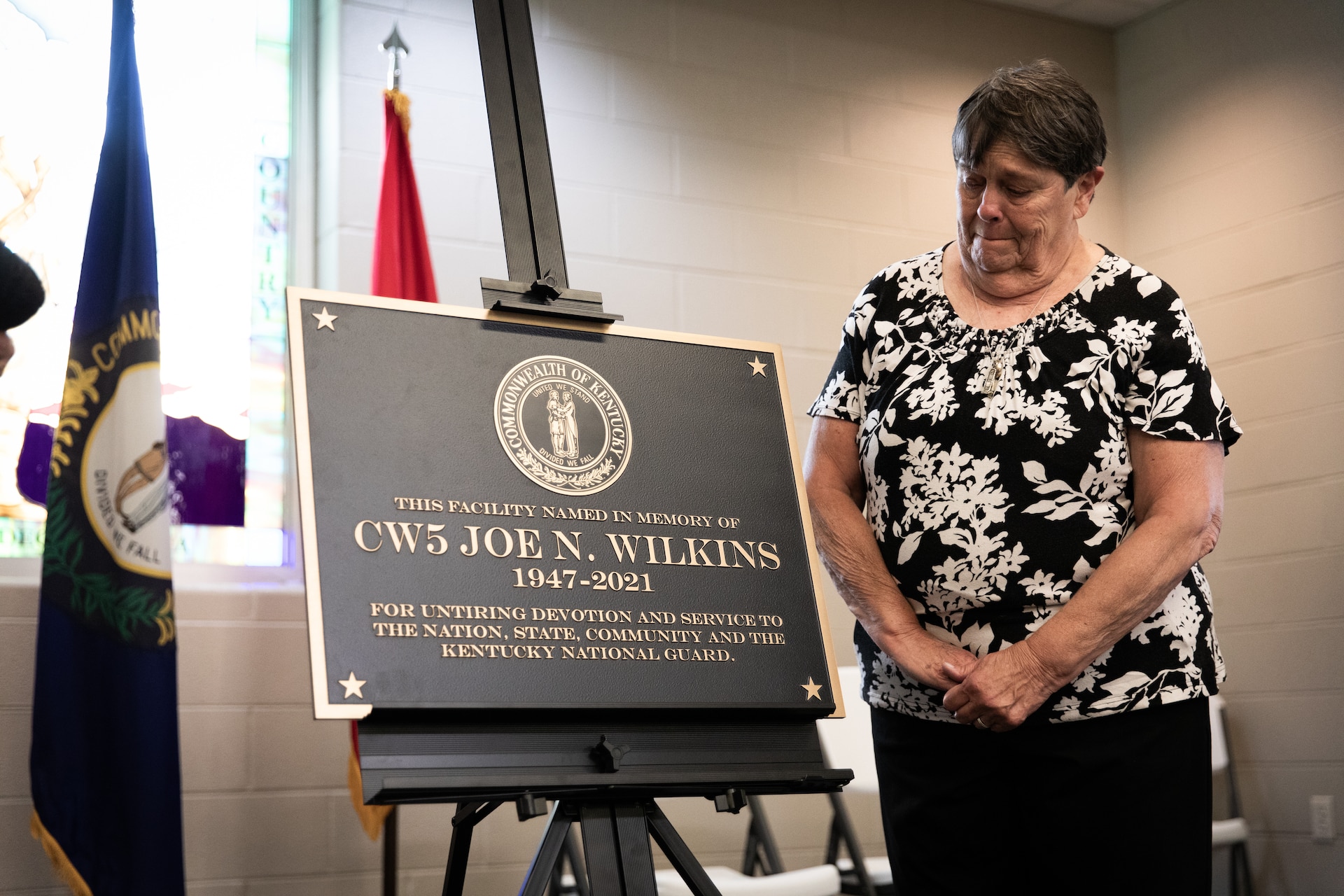 Frances Wilkins, widow of Chief Warrant Officer 5 Joe Wilkins, unveils the plaque for the building renaming in remembrance of Joe Wilkins at Wendell H. Ford Regional Training Center (WHFRTC) in Greenville, Kentucky on May 24, 2024. Joe Wilkins was one of the three full-time employees who made WHFRTC a major state training site. (U.S. Army National Guard photo by Andy Dickson)