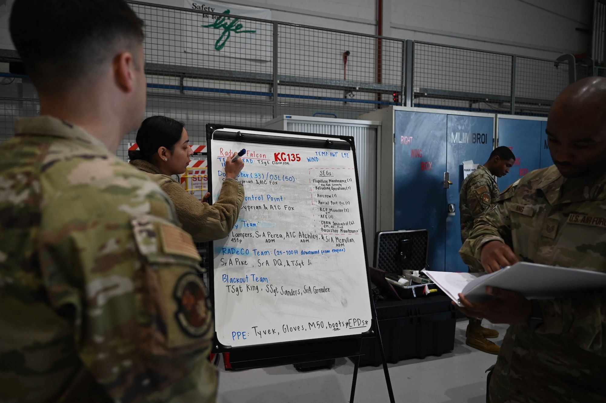 U.S. Airmen assigned to the 100th Air Refueling Wing discuss safety procedures prior to participating in exercise Radiant Falcon at Royal Air Force Mildenhall, England, May 21, 2024. The course ensures Airmen are ready to receive radiated aircraft and perform decontamination safety techniques. (U.S. Air Force photo by Senior Airman Viviam Chiu)
