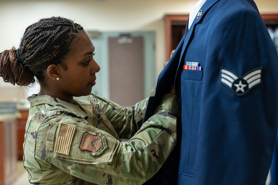 A mortuary affairs operations airman inspects a military uniform.