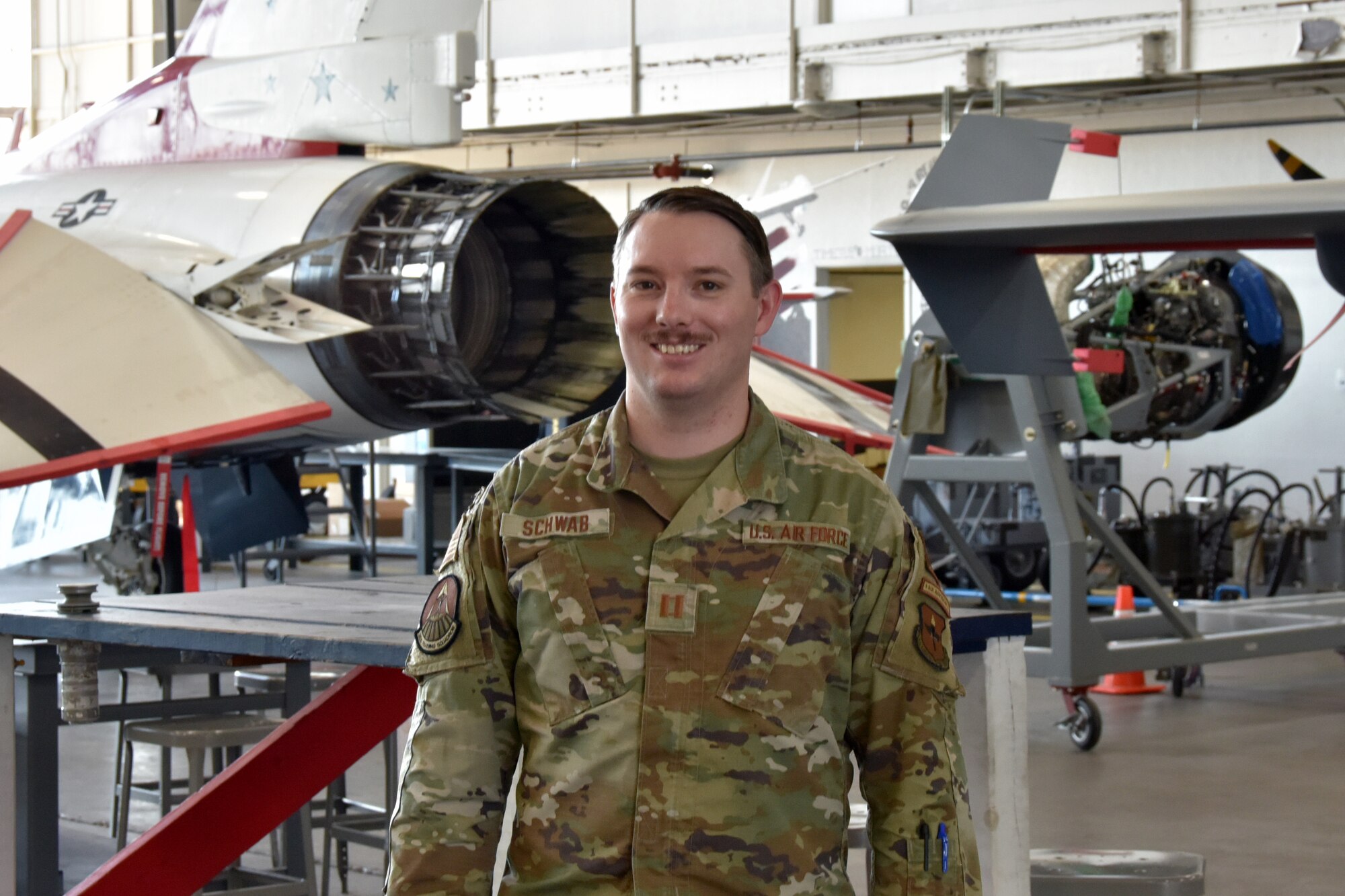 An Air Force captain stands in front of a jet
