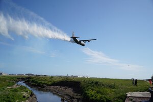 A military aircraft discharges fire retardant while in flight.