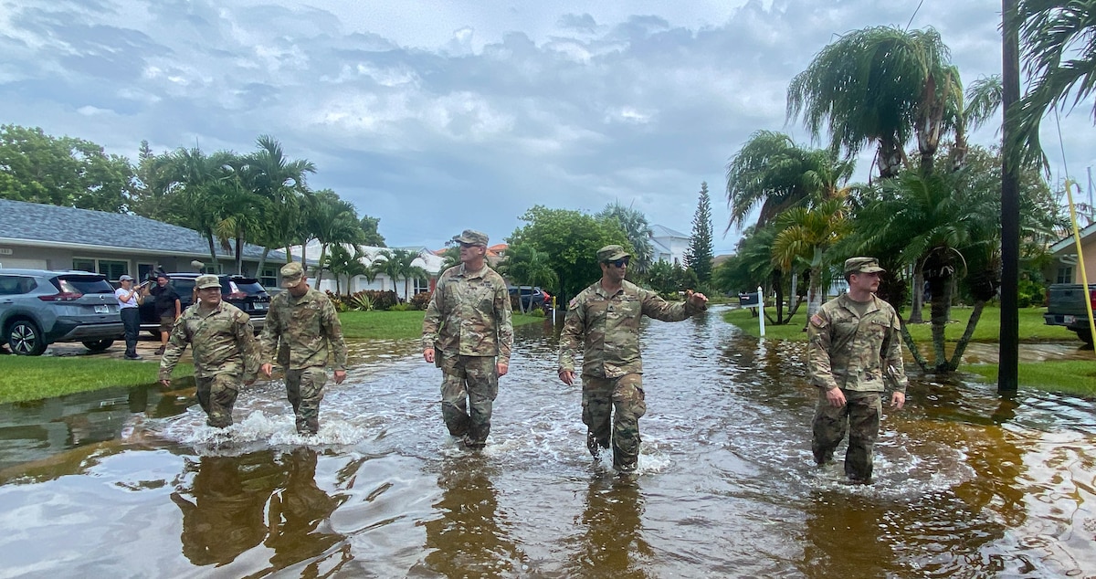 Soldiers walk through knee-high water.