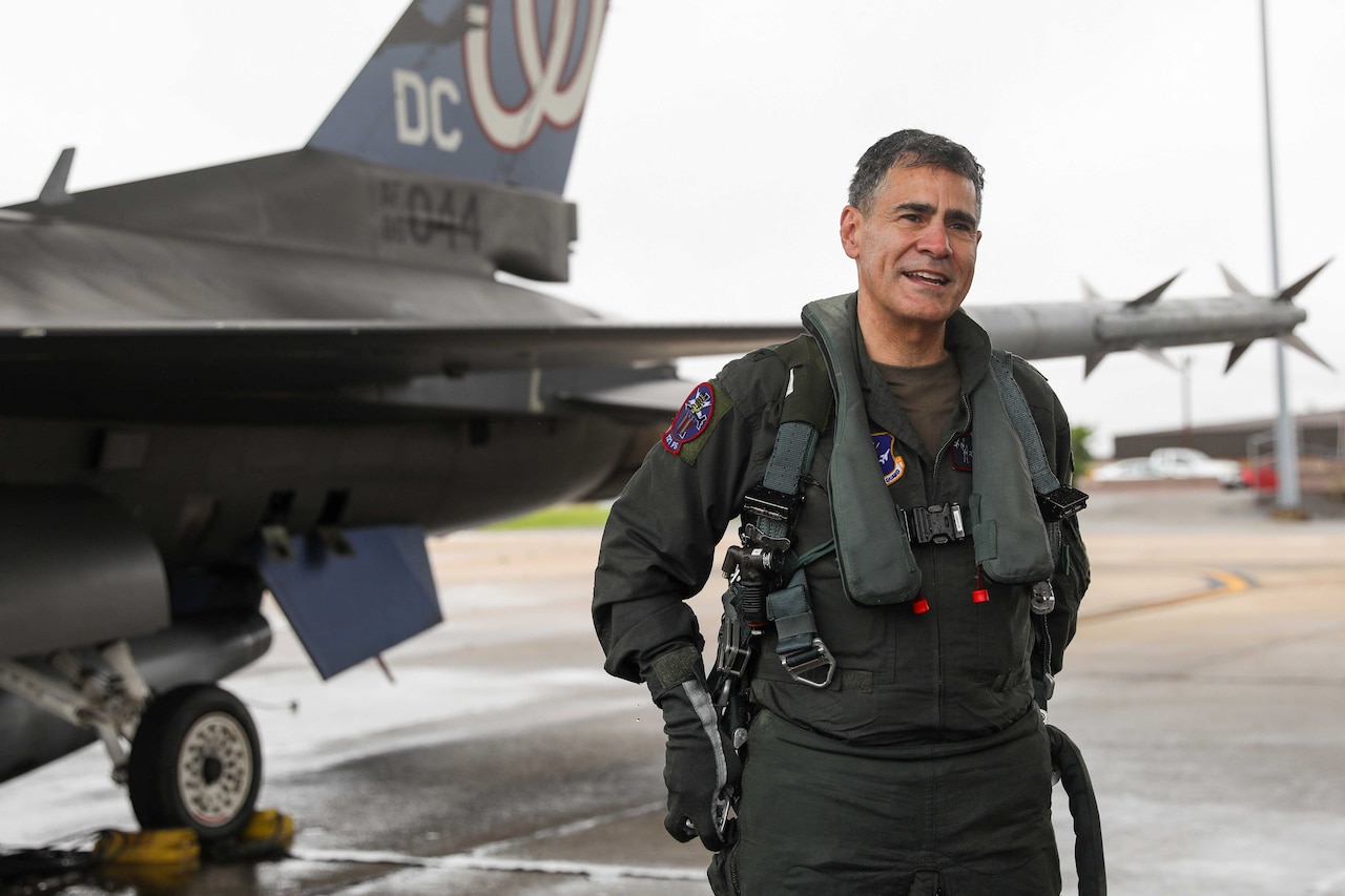A pilot stands beside a jet.