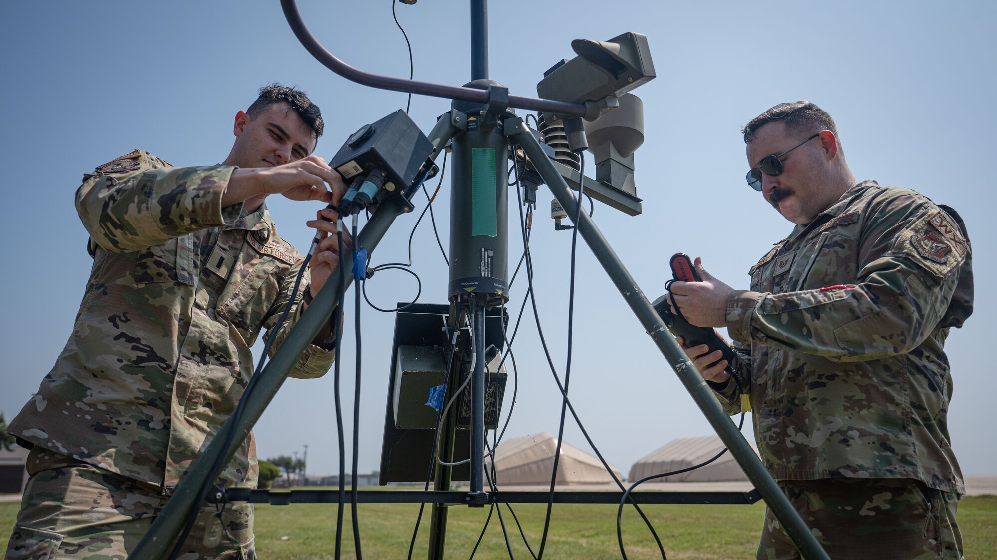 1st Lt. Evan Cade, 8th Operations Support Squadron weather flight commander, left, and Tech. Sgt. Austin Young, 8th OSS non-commissioned officer in charge of airfield weather operations, examine weather monitoring equipment.