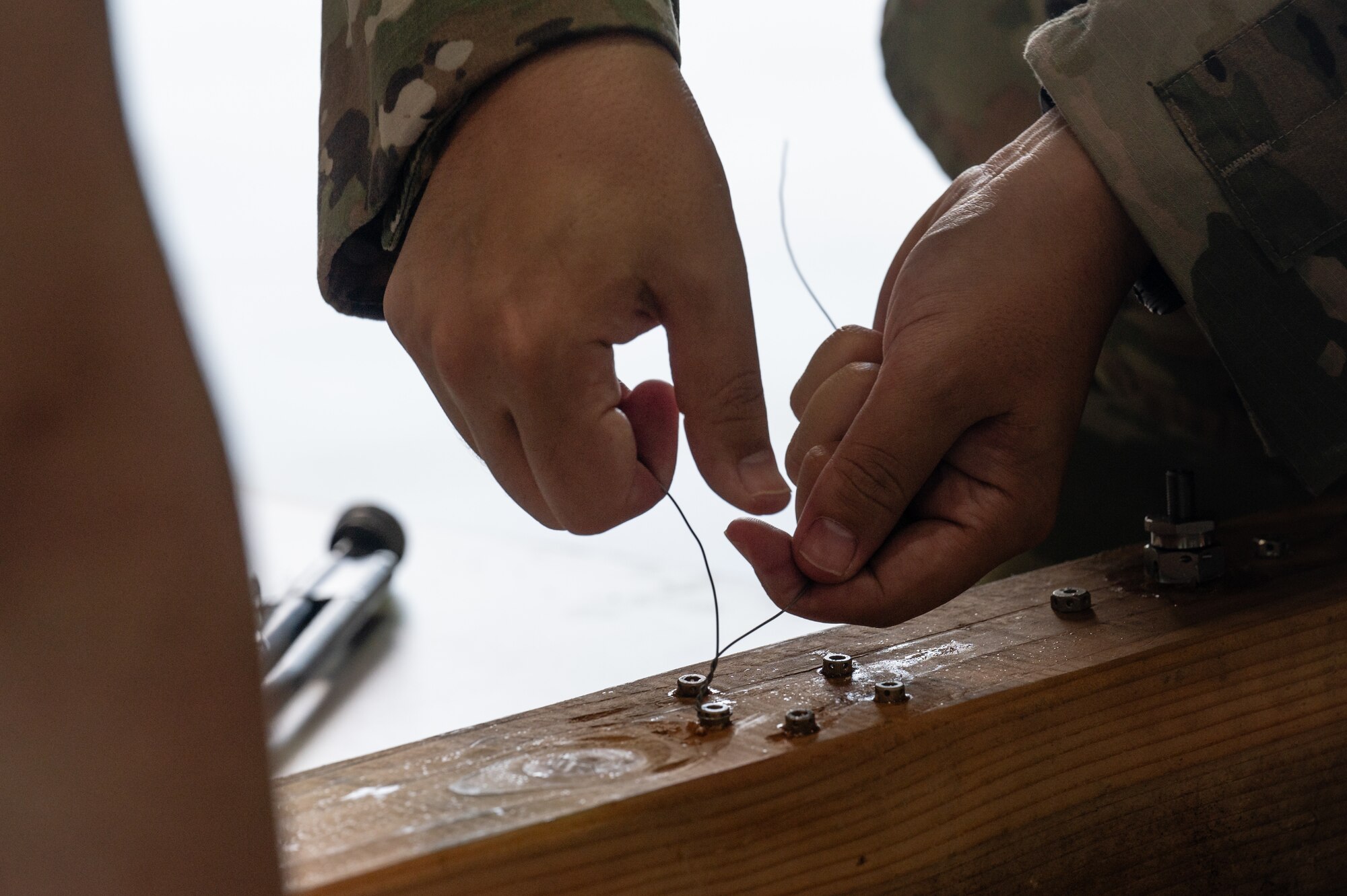 An Airman ties safety wire onto a board during a morale event.