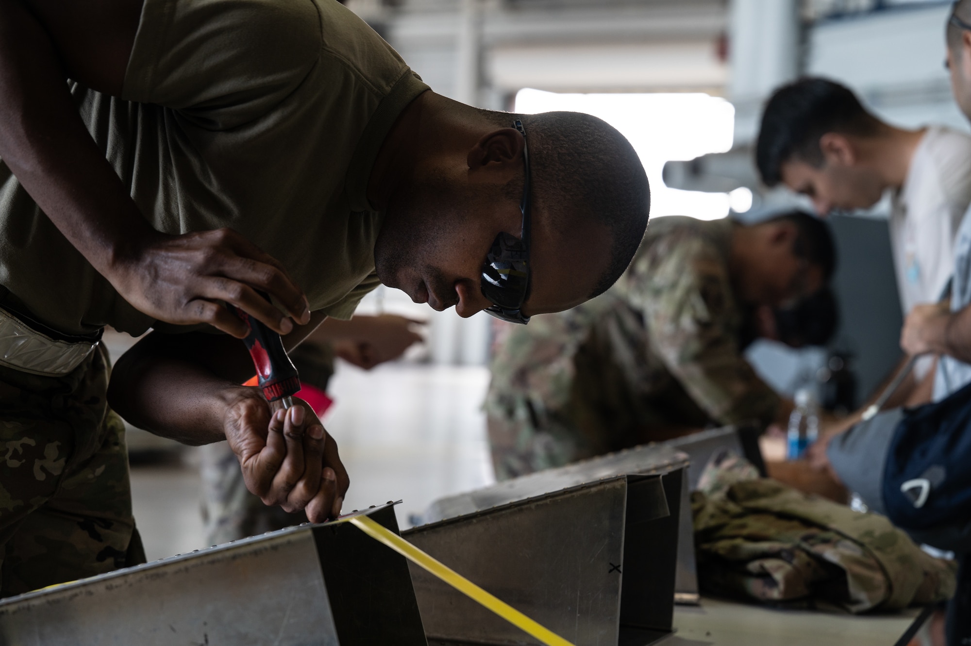 An Airman attempts to unscrew a stripped screw during a morale event.