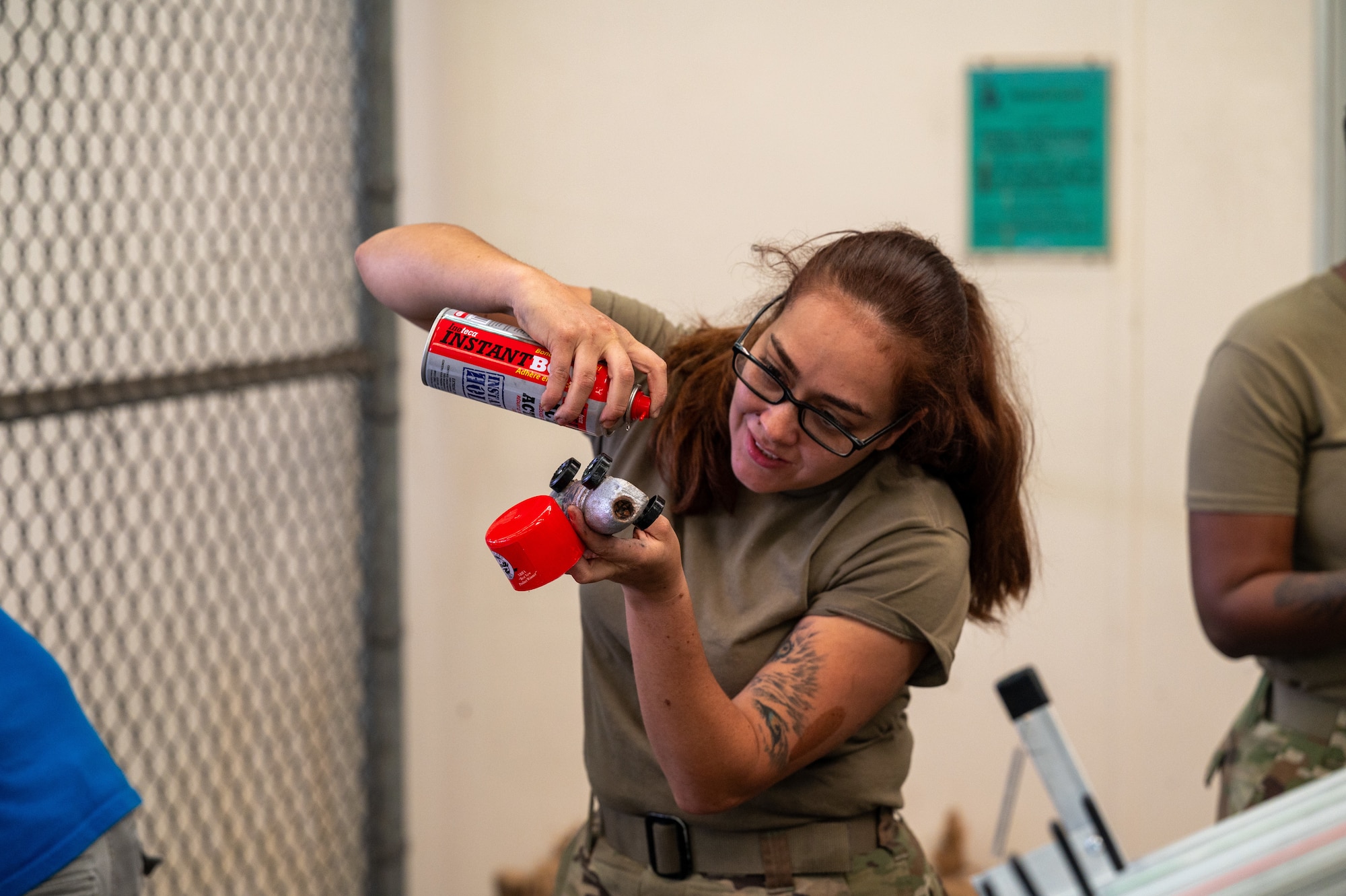 An Airman sprays paint onto a wooden toy car during a morale event.