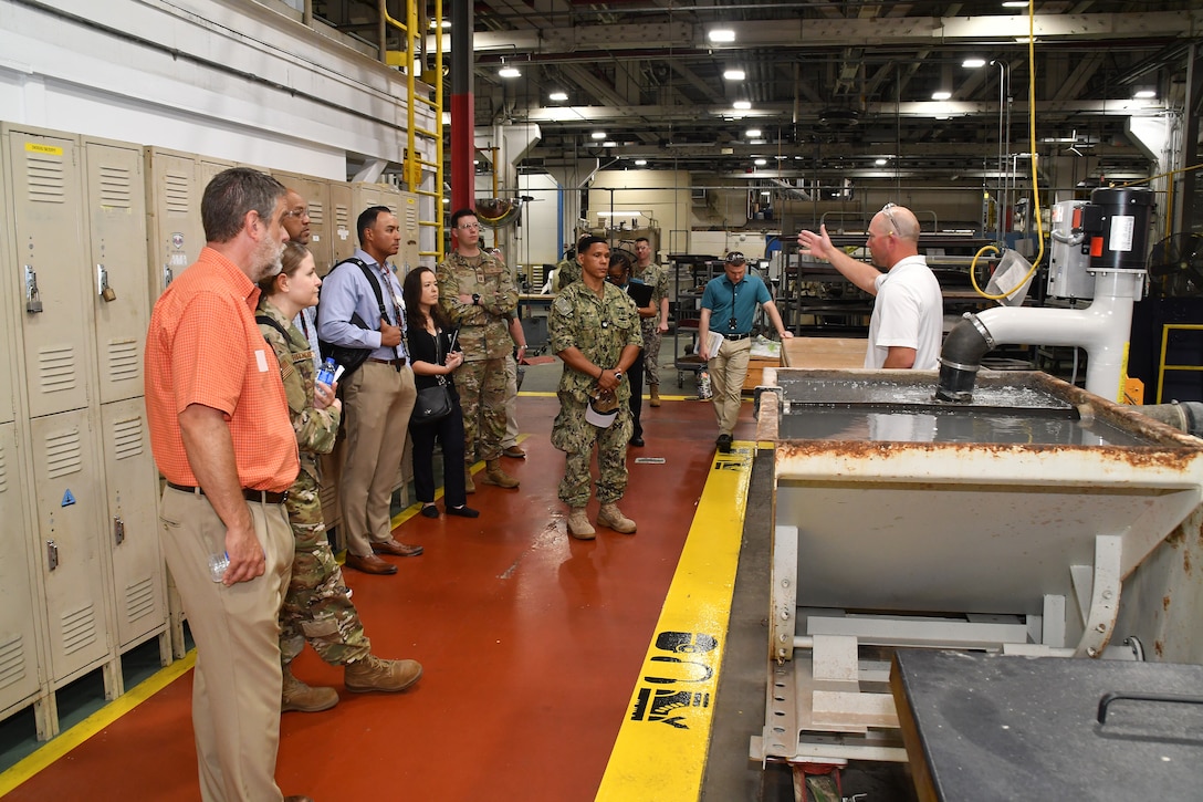 An employee explains the OMAX Water Jet to a tour group.