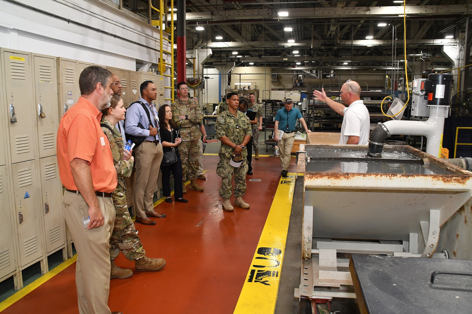 An employee explains the OMAX Water Jet to a tour group.