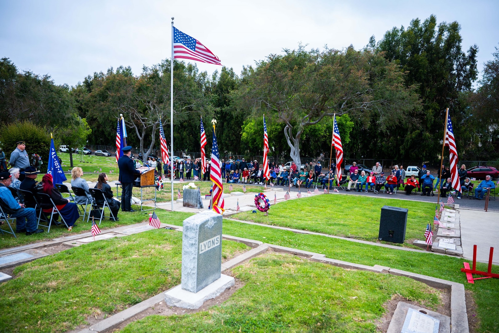 A U.S> Space Force General speaks at a podium in front of people during a Meomrial Day ceremony at a cemetery.