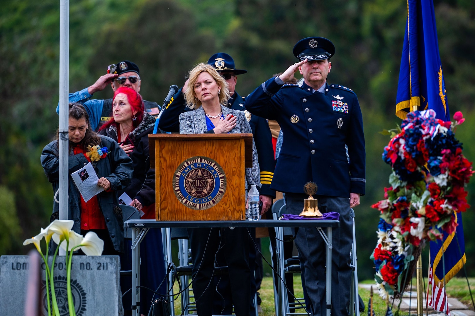 A group of people stand during a significant moment in a Memorial Day ceremony.