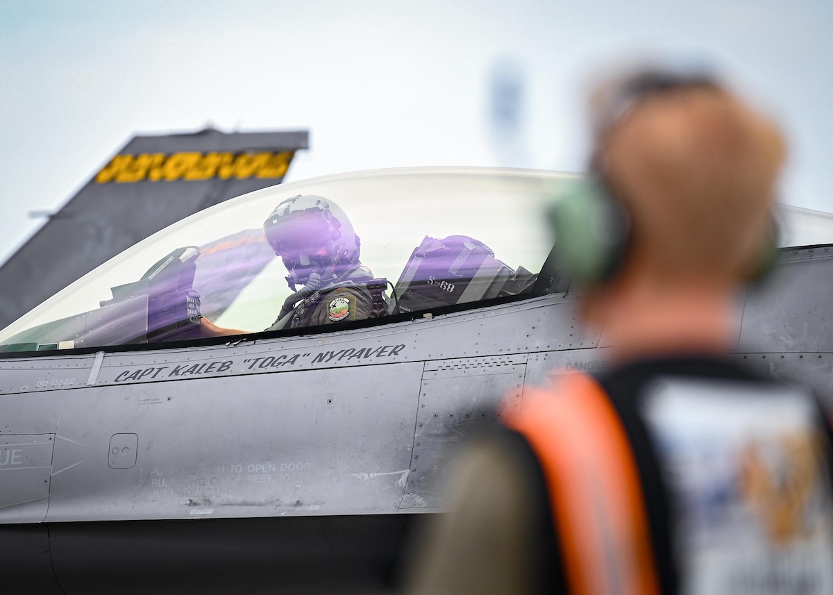 A pilots is marshaled by a crew chief before takeoff