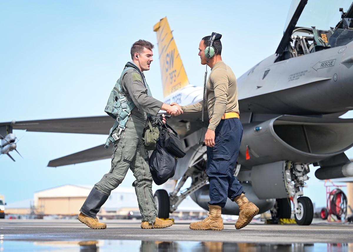 A pilot and crew chief shake hands before takeoff.