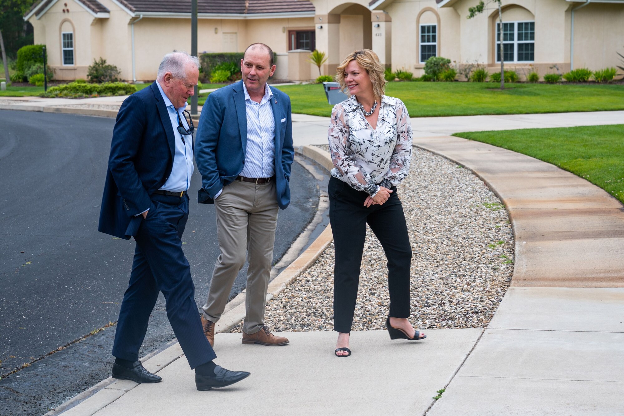 The people are walking up together on a driveway in a residential area.