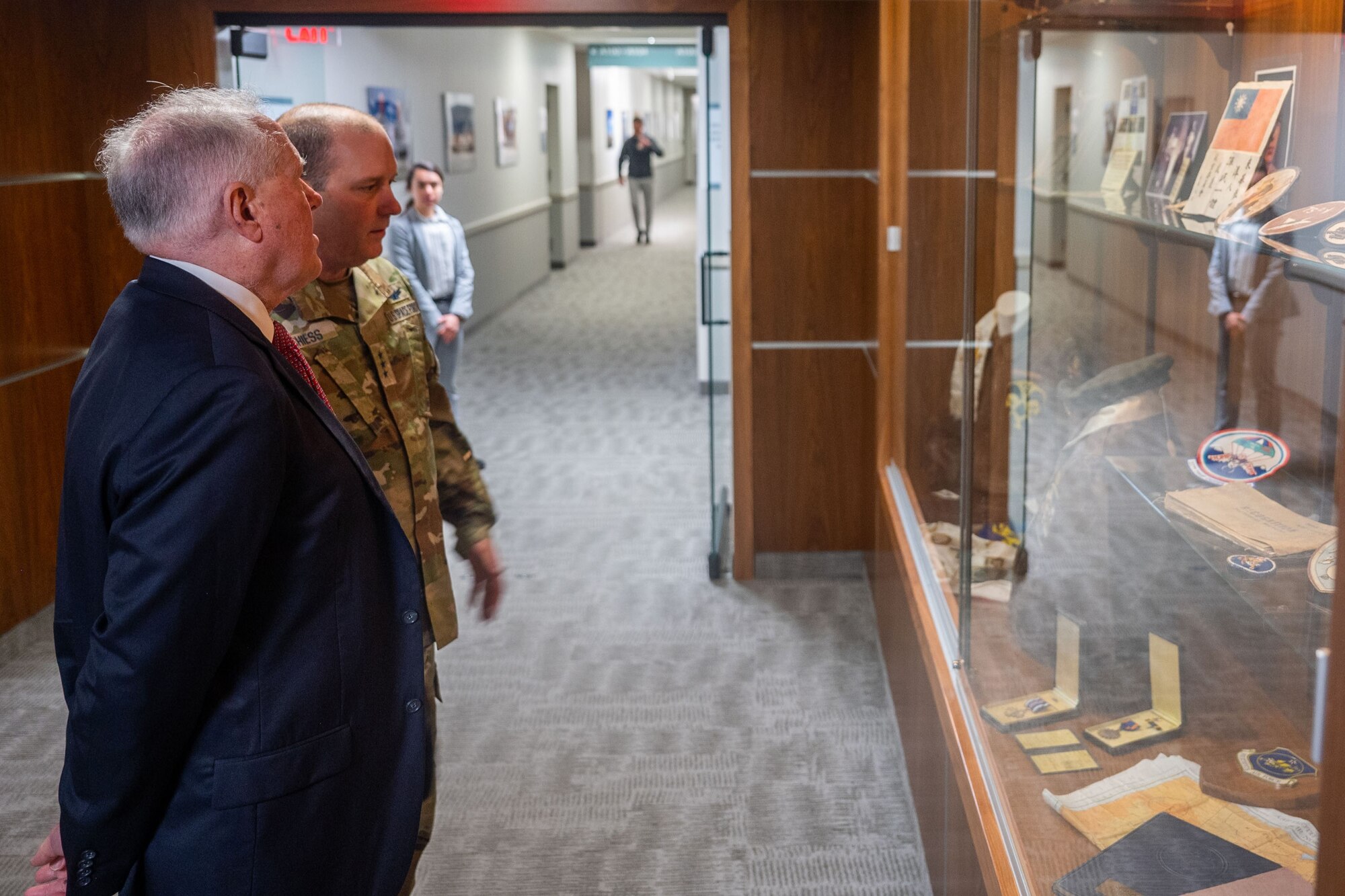 Two gentlemen are looking at a display case of old Air Force and Space memorabilia.