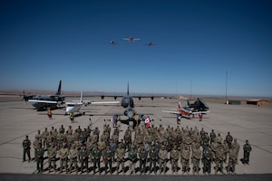 Representatives from the militaries of Peru, Colombia, Chile, Ecuador, Brazil, France and the United States pose for a group photo during the opening ceremony for Resolute Sentinel 2024 at Grupo 4 in La Joya, Peru, May 27, 2024, while military aircraft is shown behind and overhead.