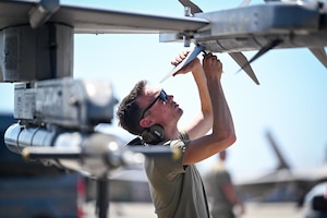 An Airman preps munitions on an aircraft