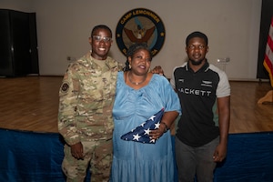 Three people pose for a photo. On the left is a man in a military uniform, the center is his mother, and on the right is his brother