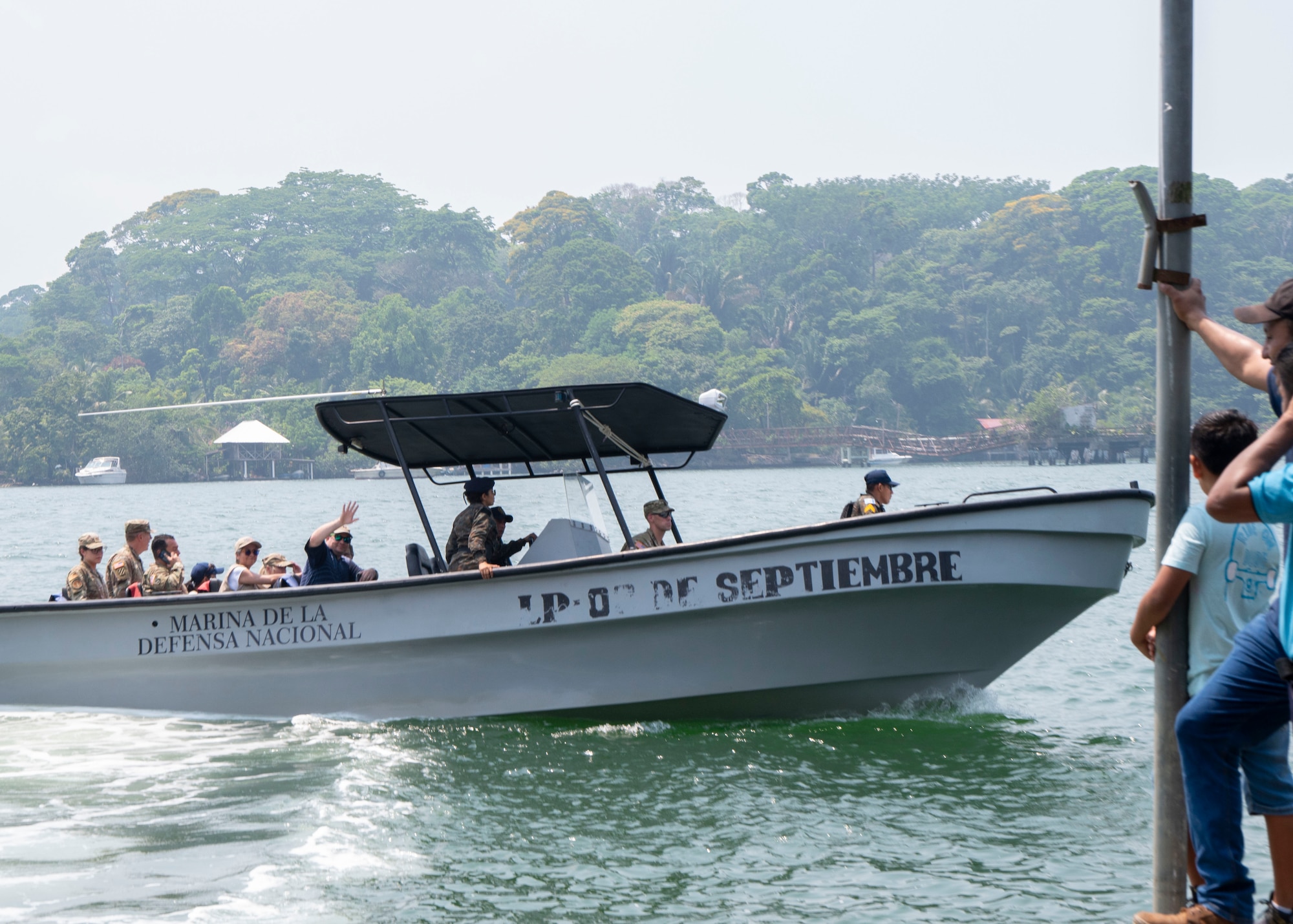 A photo of a boat with people in it waving to people who are standing on the dock.
