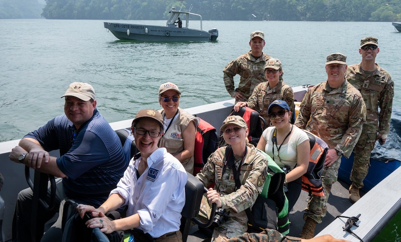 A photo of a group of people on a boat smiling at the camera.