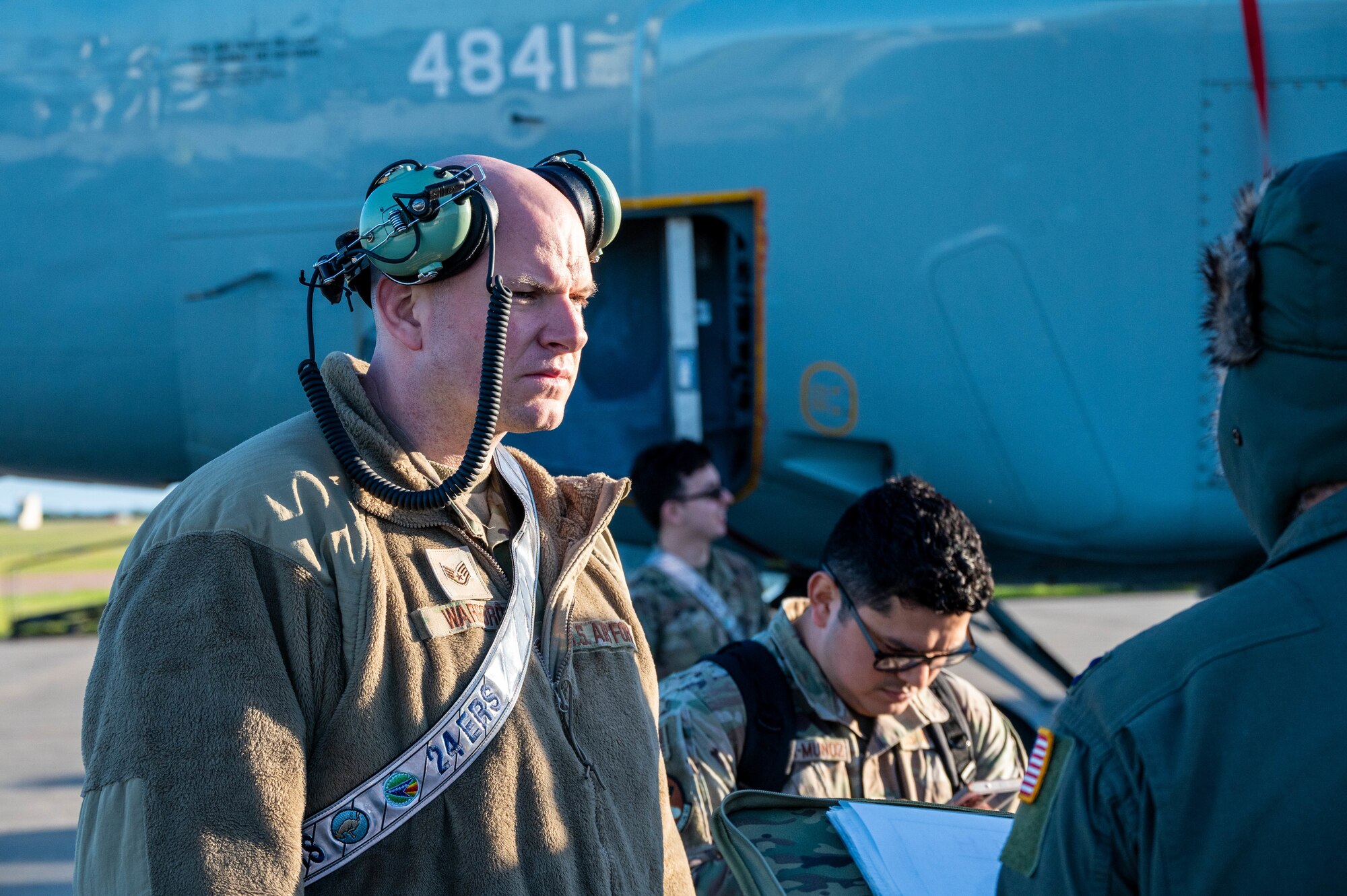 An Airman wearing ear protection listens to another Airman speak