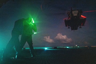 Sailors signal to a CH-53E Super Stallion helicopter from VMM-165  aboard USS Somerset (LPD 25) in the South China Sea.
