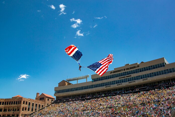 A skydiver parachutes onto the field with the American flag as part of a Memorial Day tribute following the BOLDERBoulder 10-kilometer race at Folsom Field, Boulder, Colorado, May 27, 2024. Marine Corps Recruit Depot and Western Recruiting Region sent Marines to represent the command during the 2024 BOLDERBoulder 10k race to engage with the local community and showcase the spirit of the organization. (U.S. Marine Corps photo by Master Sergeant Ezekiel R. Kitandwe)