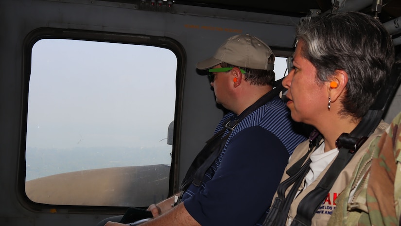 A photo of two people looking out a window of a helicopter.