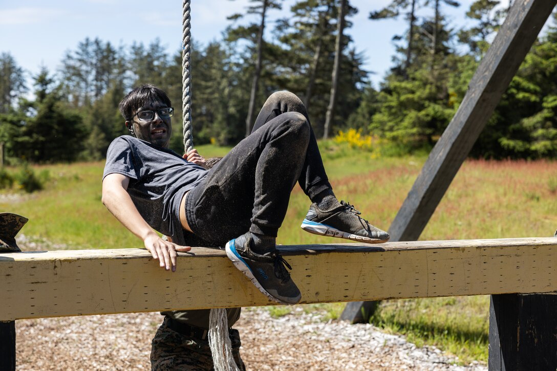 A guest attending the Recruiting Station Portland pool function rope swings onto a beam while completing an obstacle course at Camp Rilea Armed Forces Training Center in Warrenton, Oregon, May 18, 2024. Pool functions are held to prepare poolees for the mental and physical rigors of recruit training. (U.S. Marine Corps photo by Cpl. Andrew Bray)
