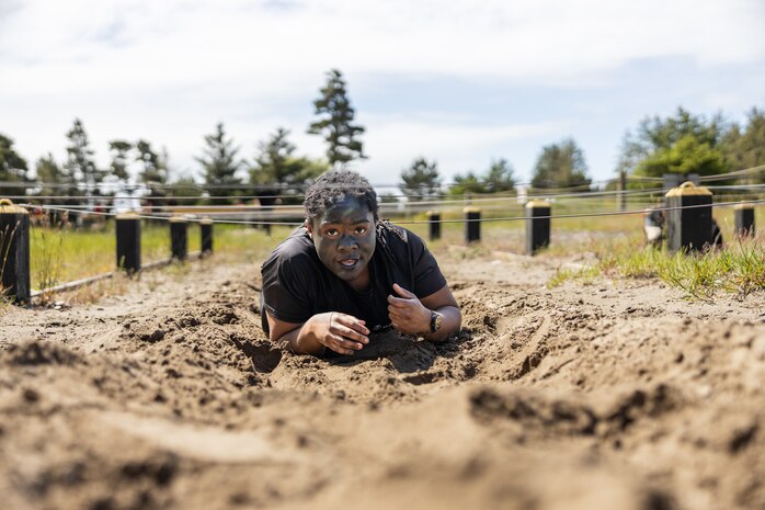 A guest attending the Recruiting Station Portland pool function low crawls through sand while completing an obstacle course at Camp Rilea Armed Forces Training Center in Warrenton, Oregon, May 18, 2024. Pool functions are held to prepare poolees for the mental and physical rigors of recruit training. (U.S. Marine Corps photo by Cpl. Andrew Bray)