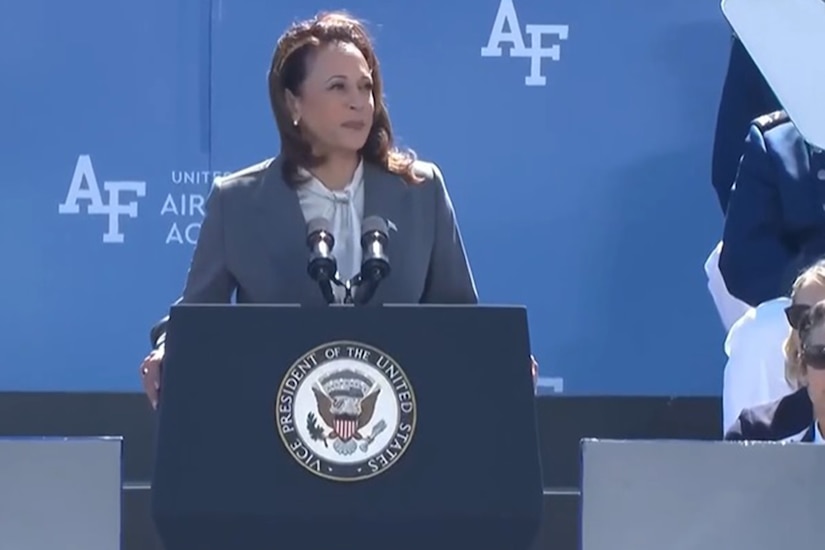 A person speaks at a podium with the Air Force Academy logo behind them.