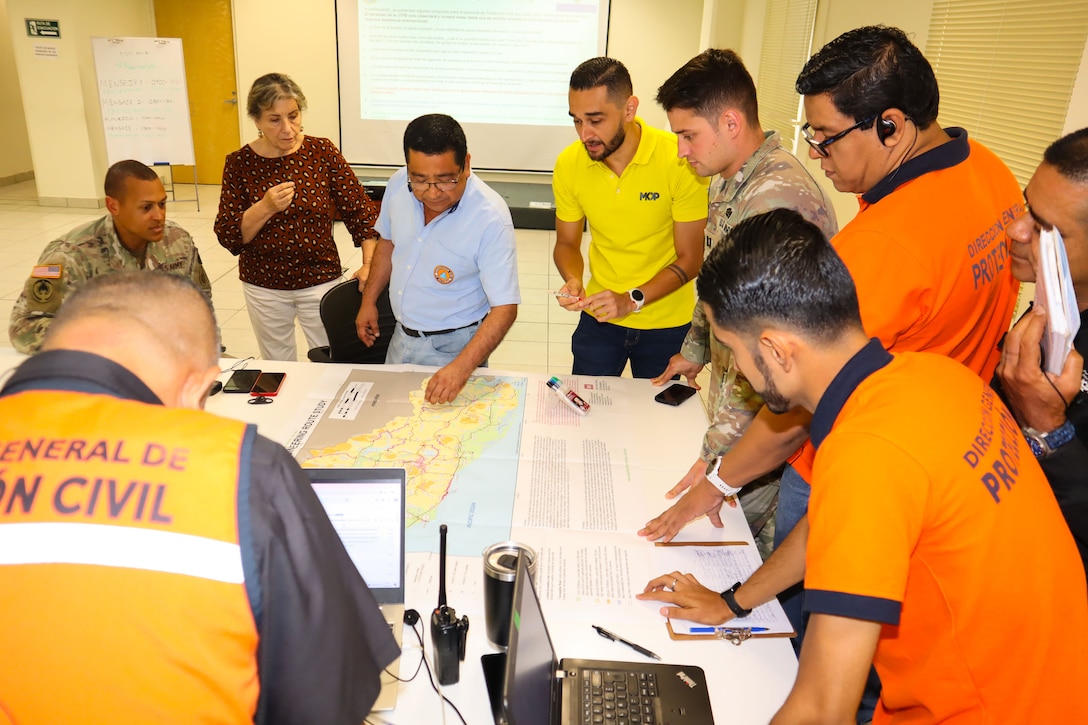 A photo of a group of personnel discussing plans at a map.