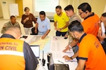 A photo of a group of personnel discussing plans at a map.