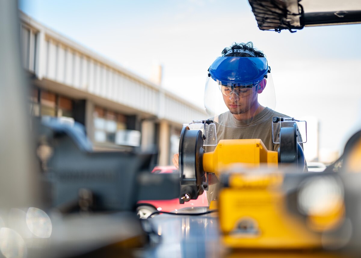 An Airman grinds metal.