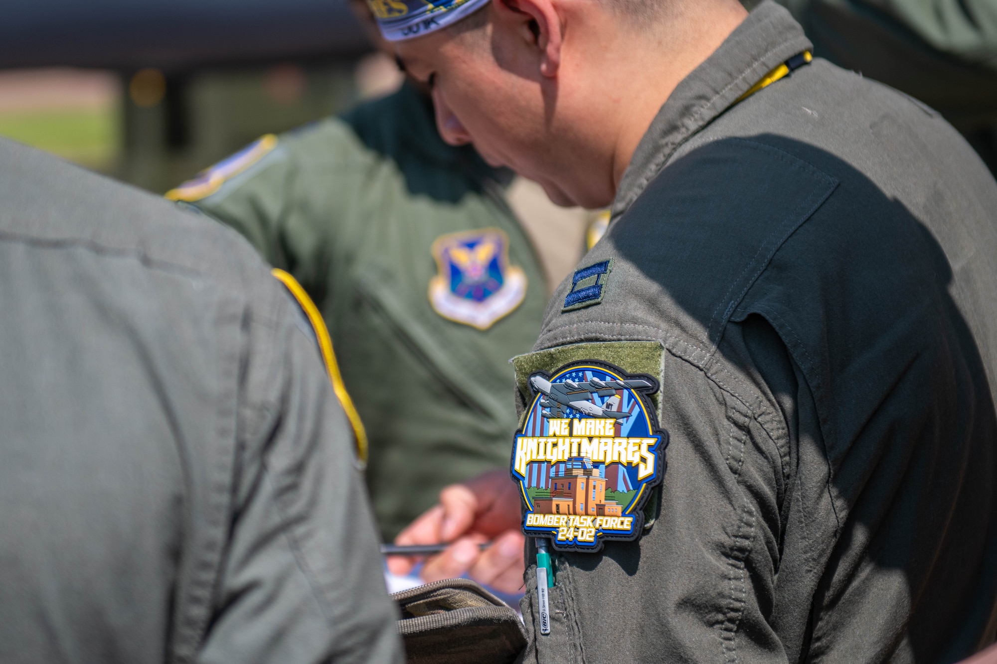 A morale patch reads “WE MAKE KNIGHTMARES” on the sleeve of a flight suit
